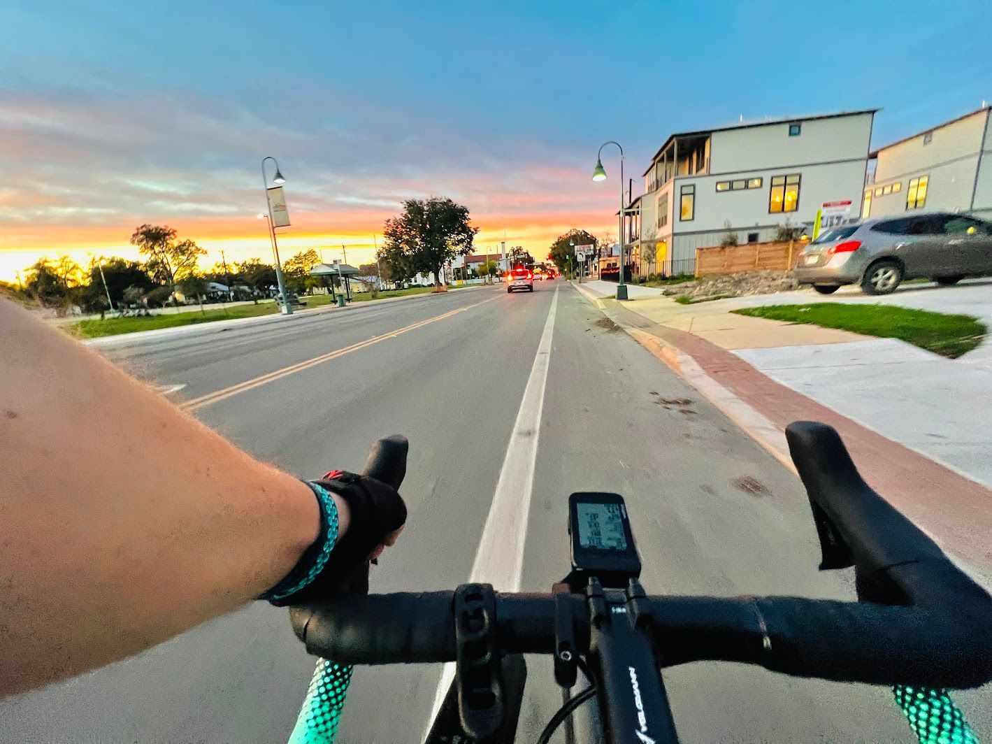 A person is riding a bike down a street at sunset.