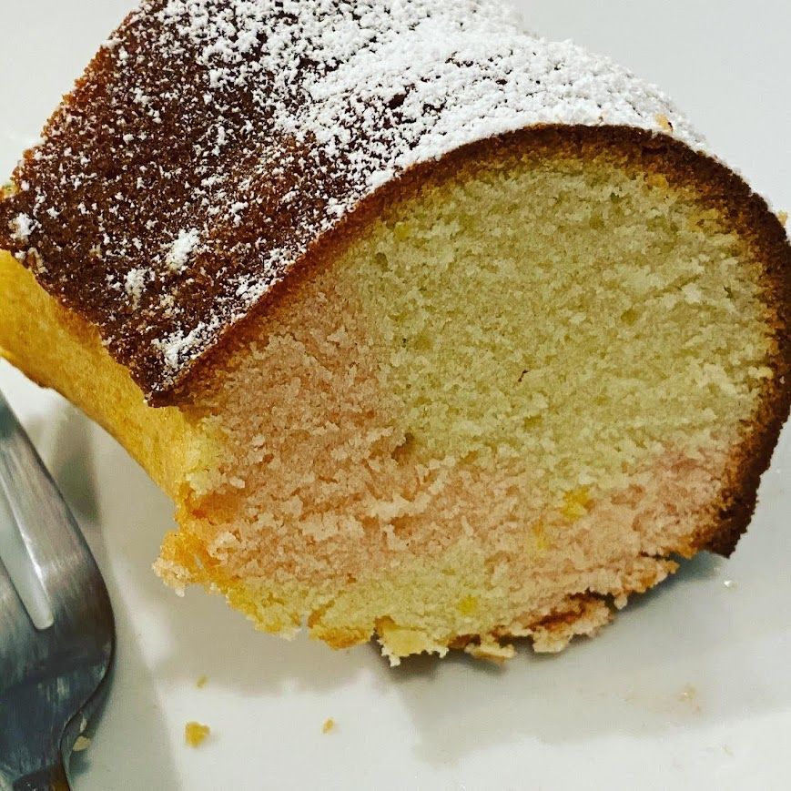 A slice of cake with powdered sugar on top next to a fork