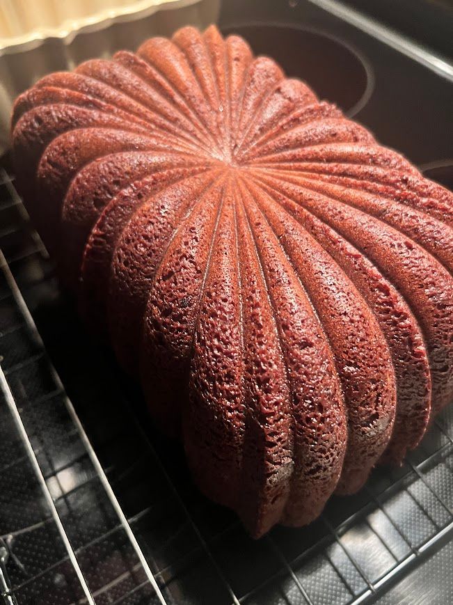 A loaf of red velvet cake is sitting on a cooling rack.