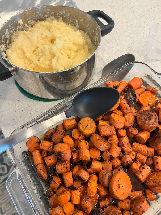 A pan of carrots next to a pot of mashed potatoes
