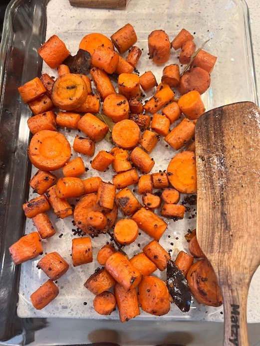 A tray of carrots with a wooden spatula on top