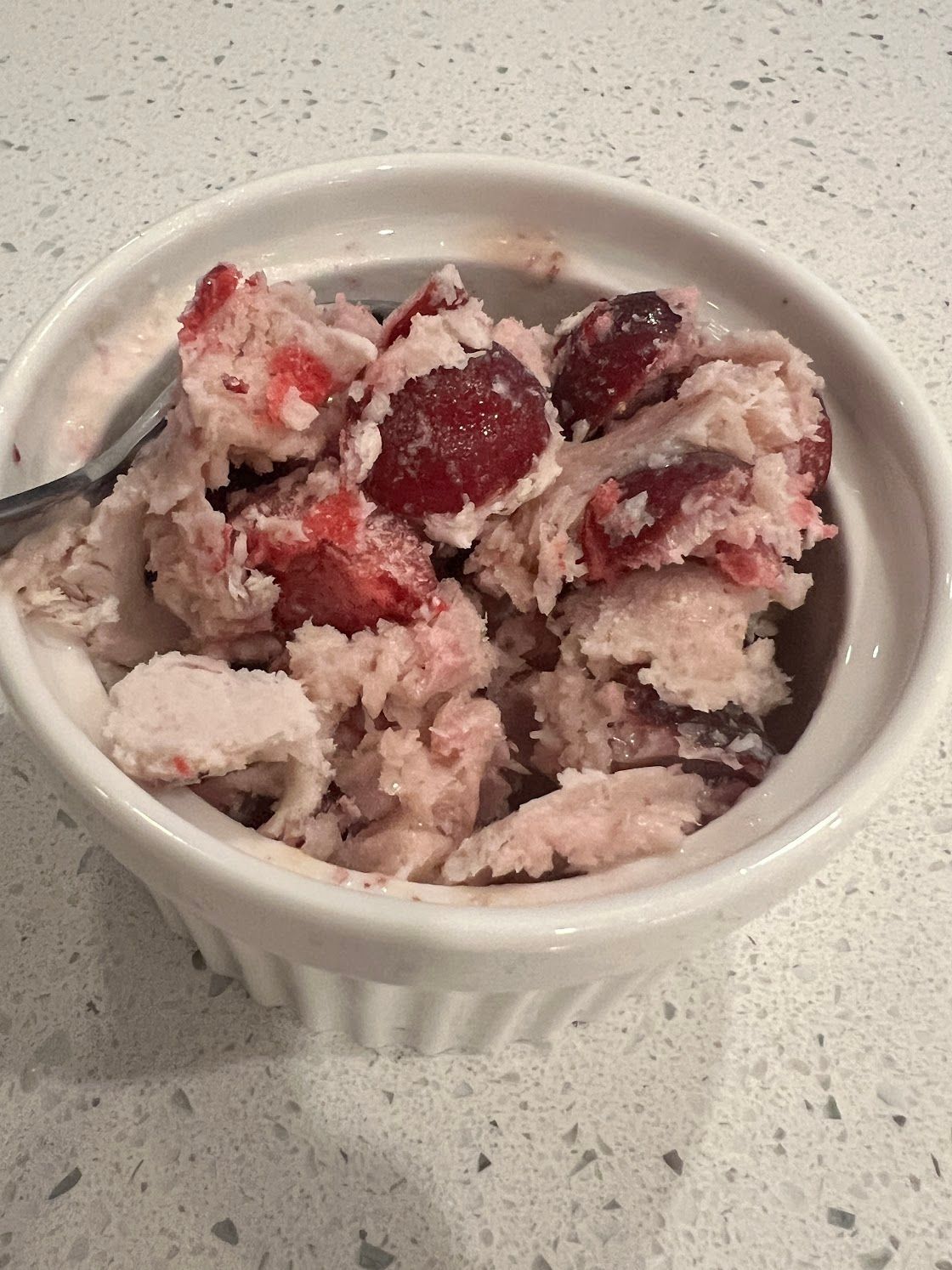 A bowl of ice cream with strawberries and a spoon in it