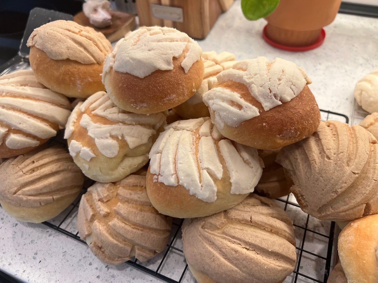 A bunch of conchas are sitting on top of each other on a cooling rack.