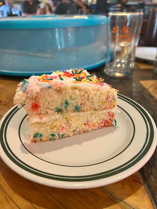 A slice of cake with sprinkles on it is on a plate.