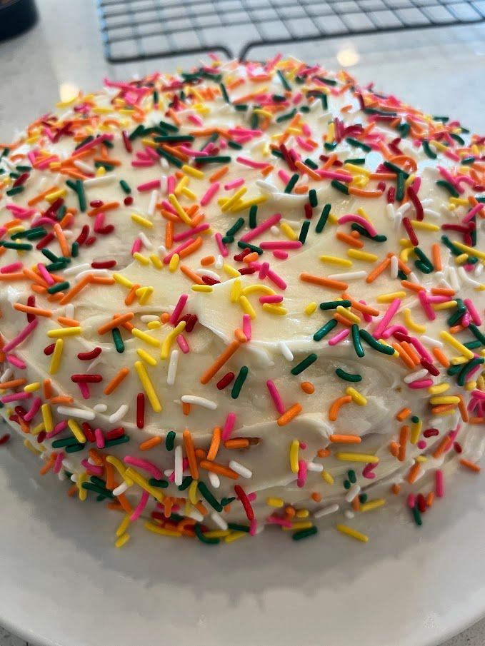 A cake with white frosting and colorful sprinkles on it