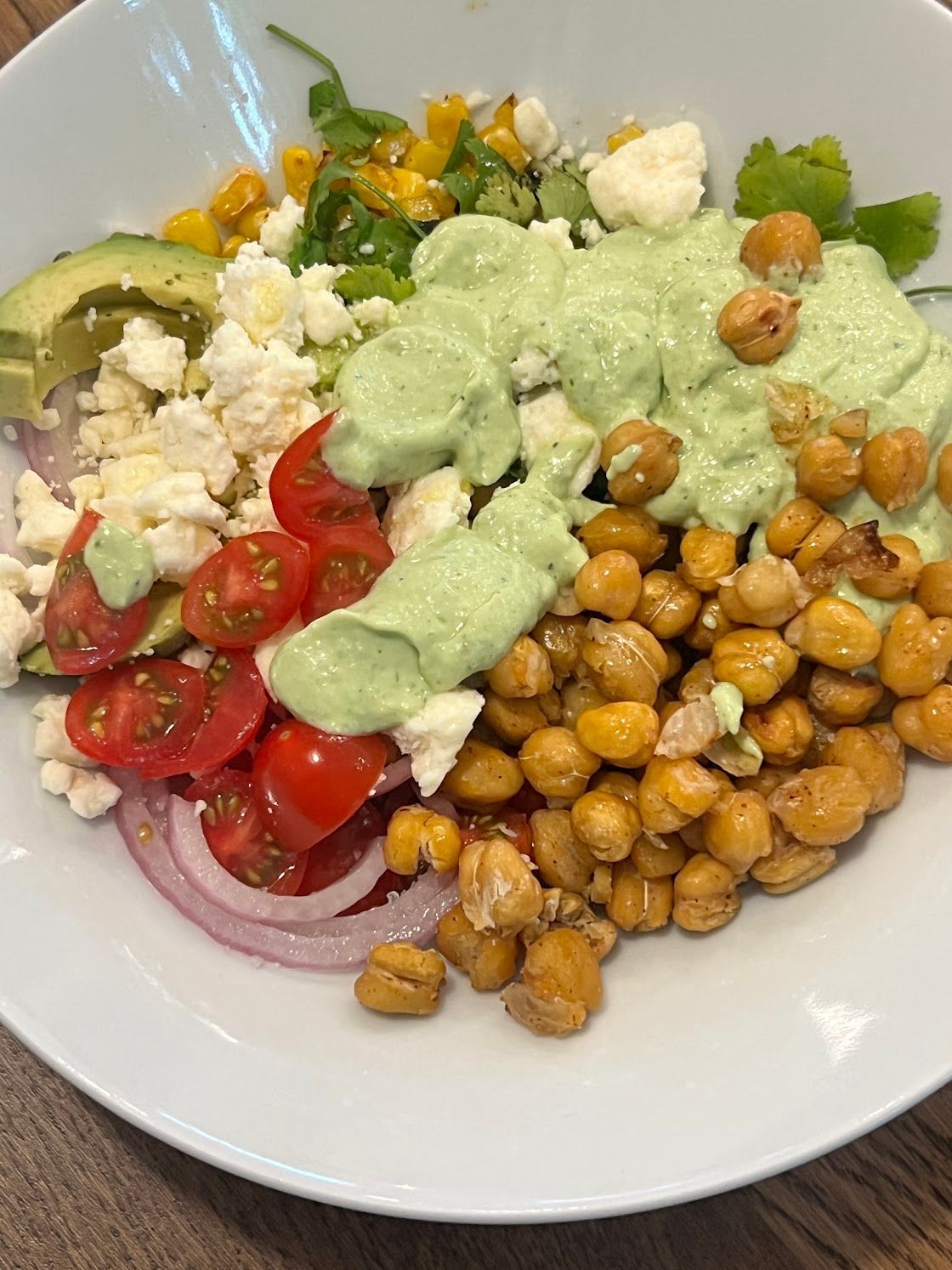 A white plate topped with a salad of chickpeas , tomatoes , onions and feta cheese.