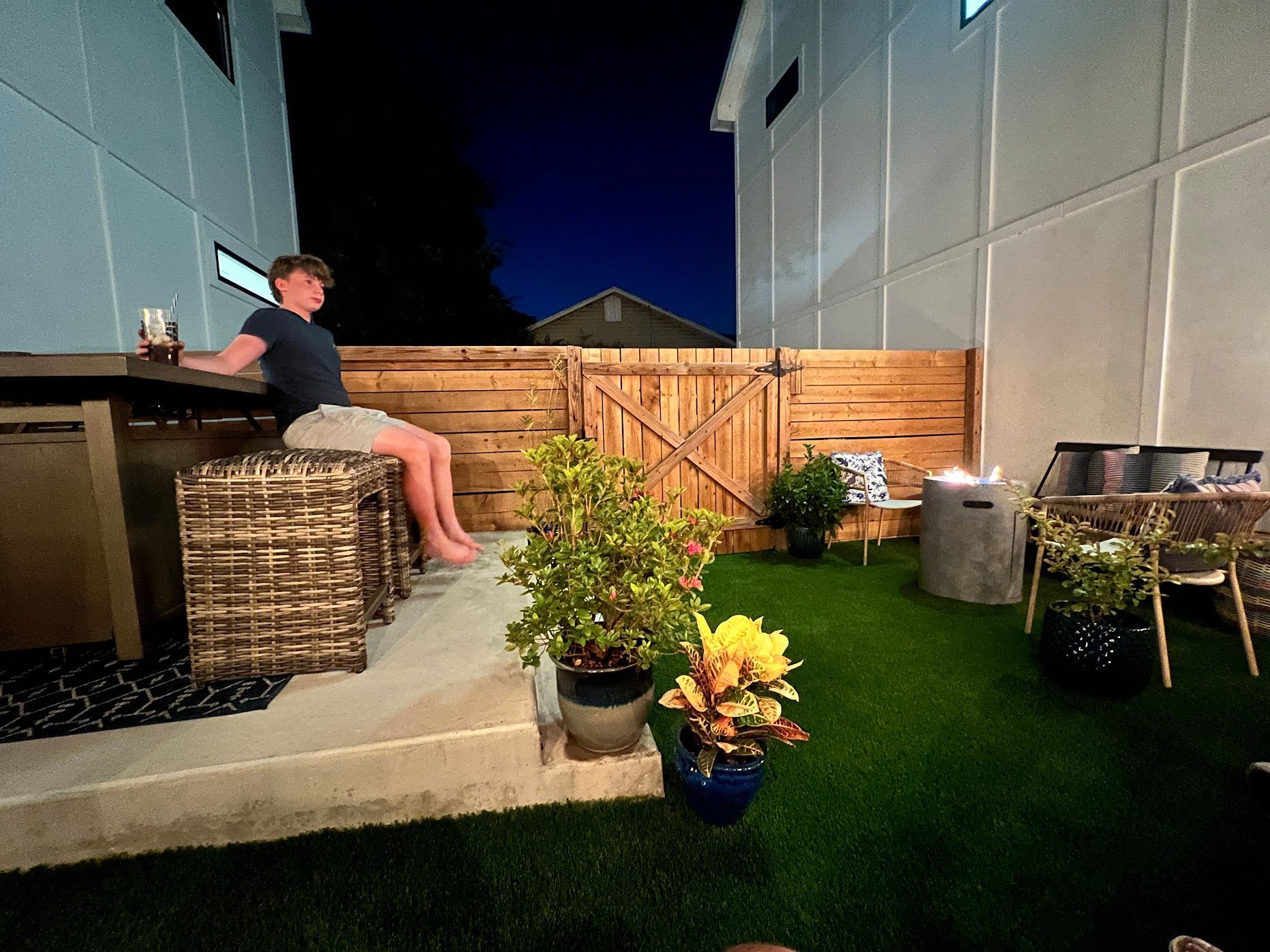 A man is sitting at a table in a backyard at night.