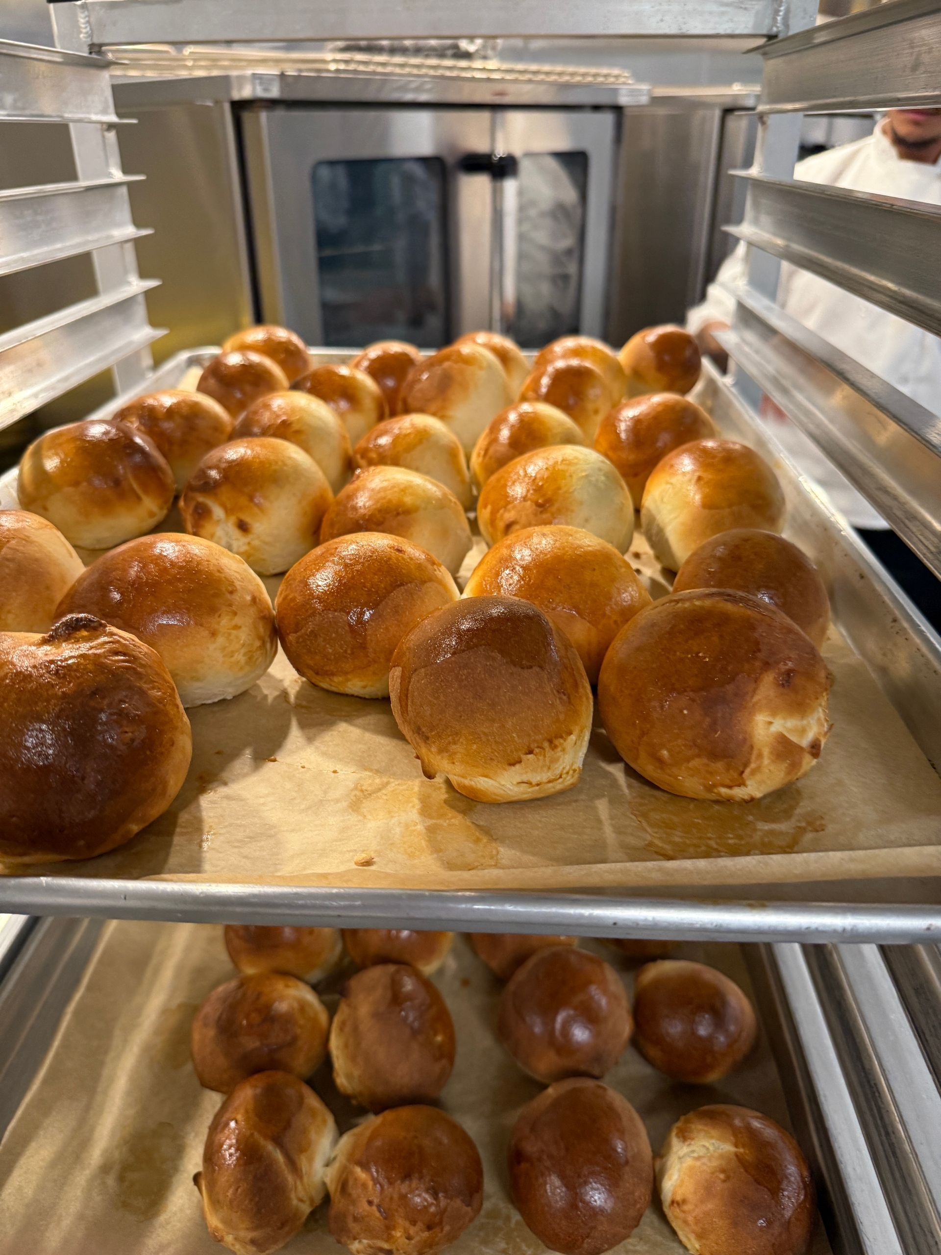 A bunch of rolls are sitting on a tray in a bakery.