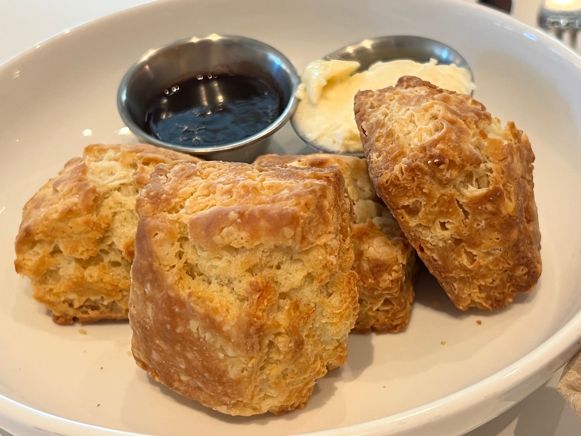 A plate of biscuits with butter and syrup on a table.