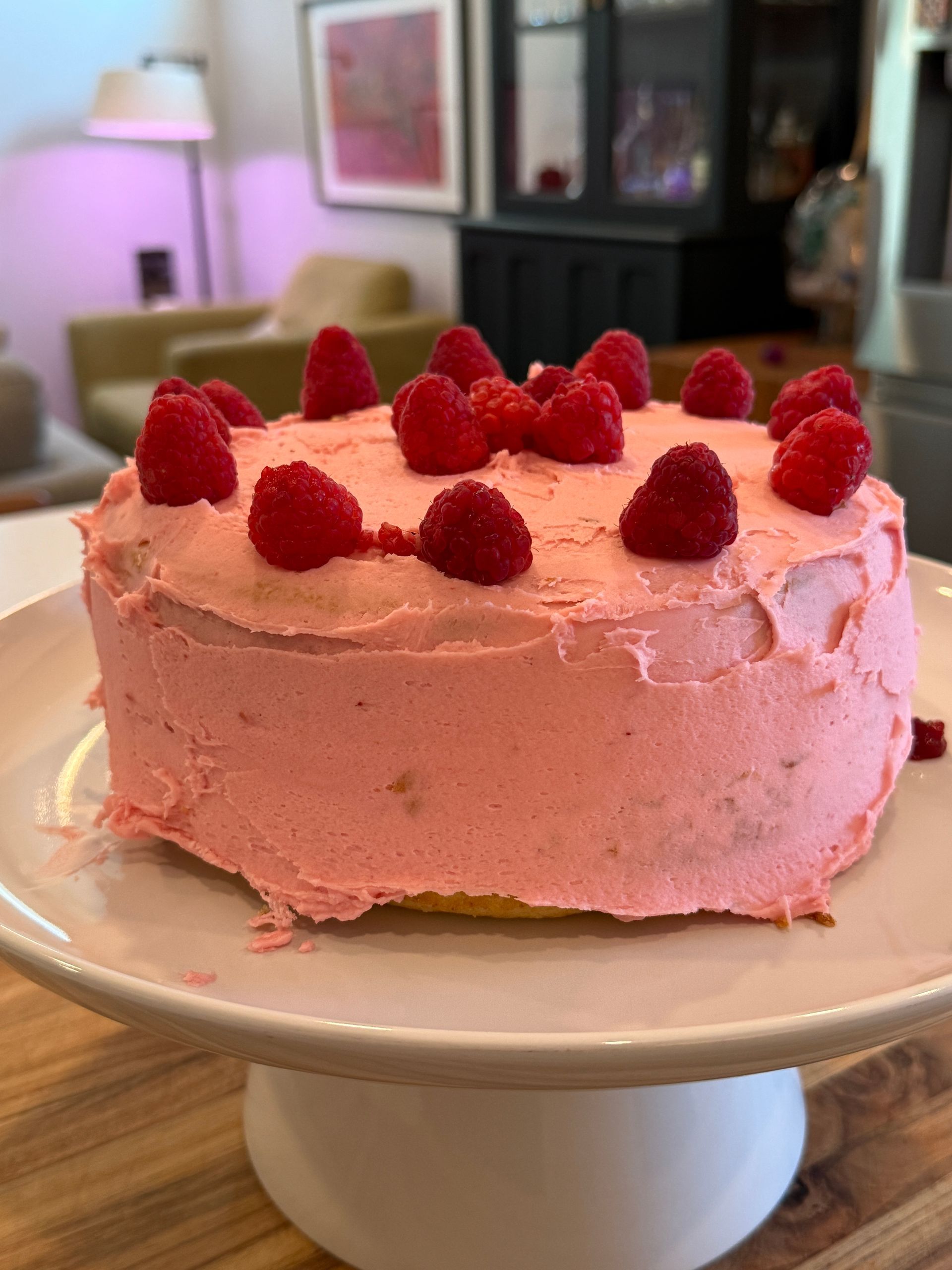 a pink raspberry cake is sitting on a plate