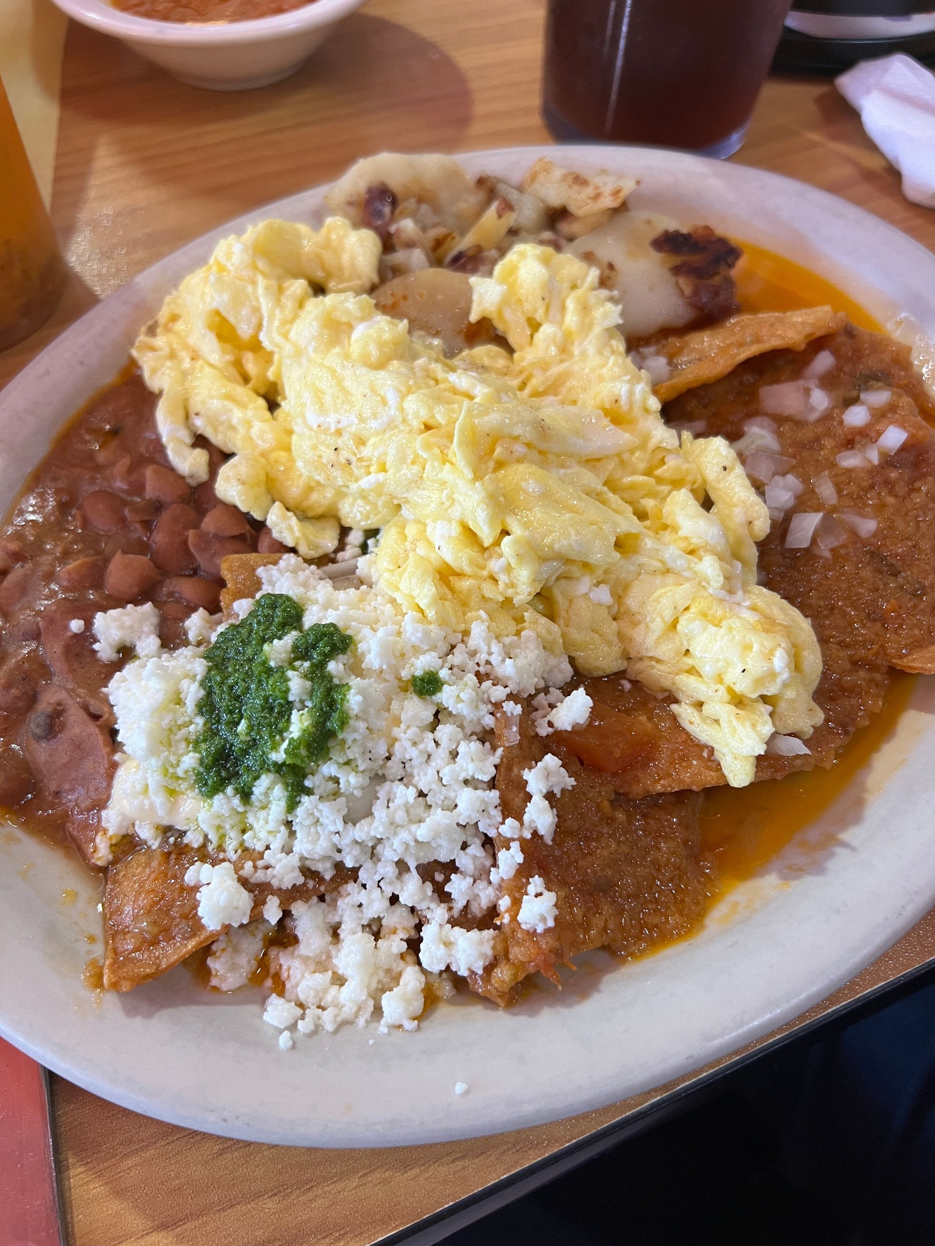 A plate of food with eggs , beans , and cheese on a table.
