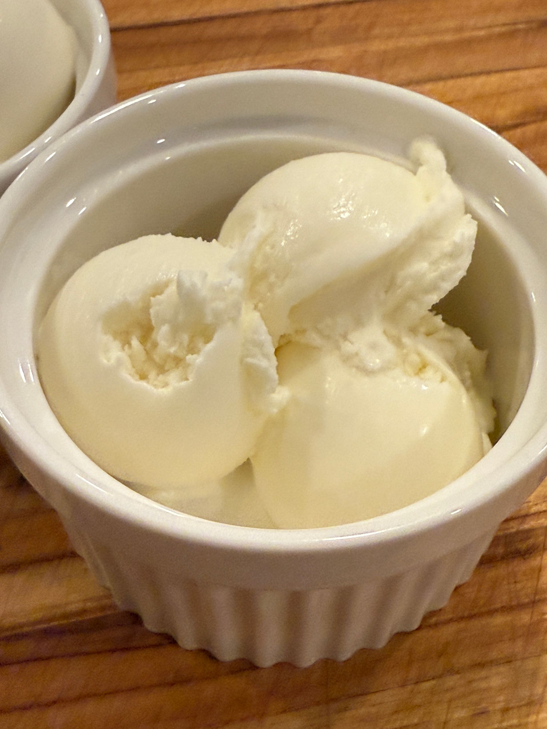 A bowl of ice cream is sitting on a wooden table.