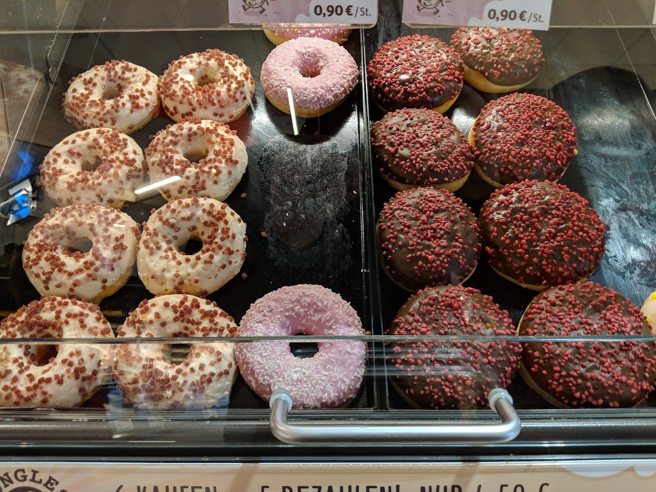 A variety of donuts are displayed in a glass case