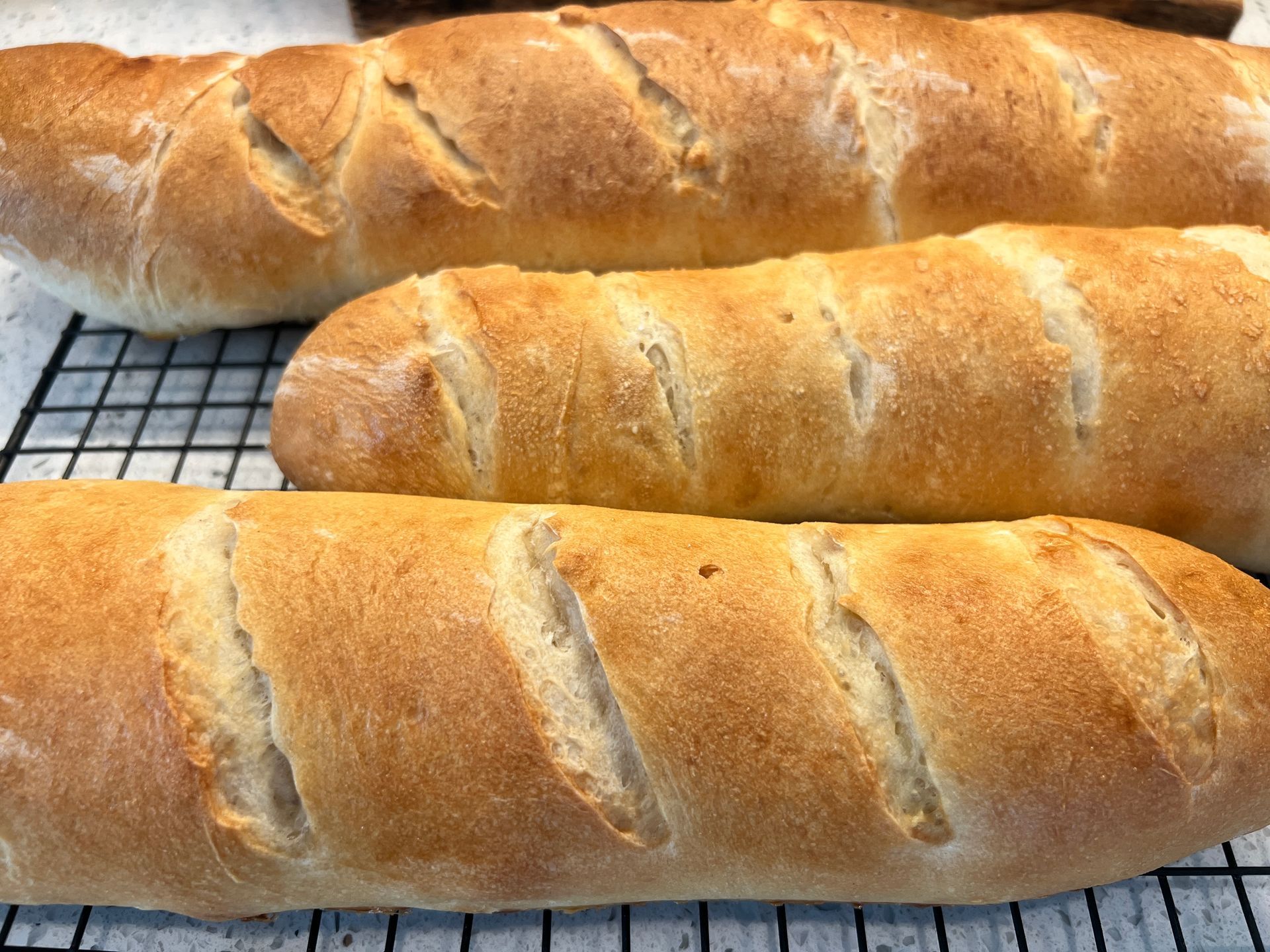 Three loaves of bread are sitting on a cooling rack.