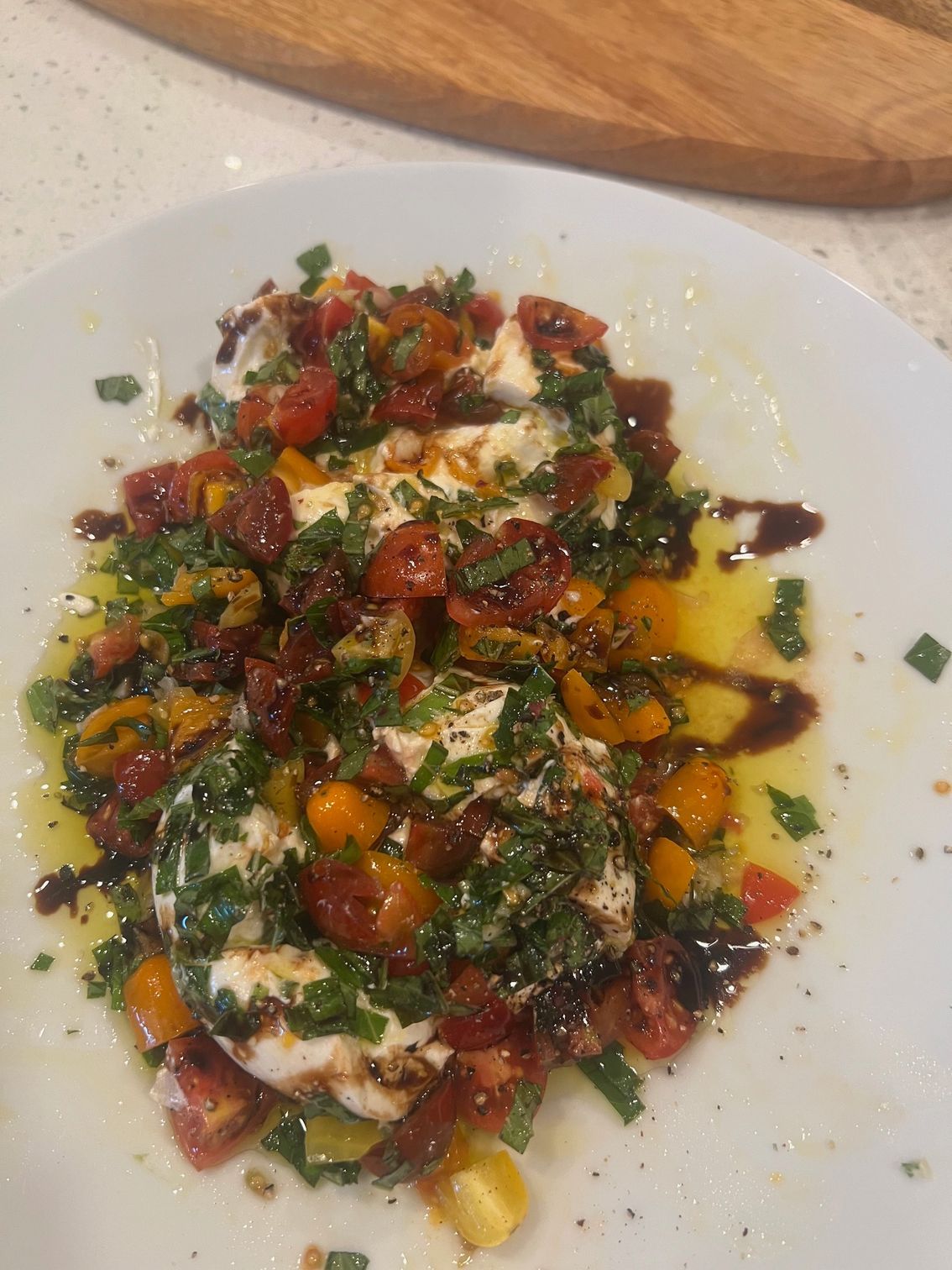 A white plate topped with a salad of tomatoes , mozzarella and parsley.