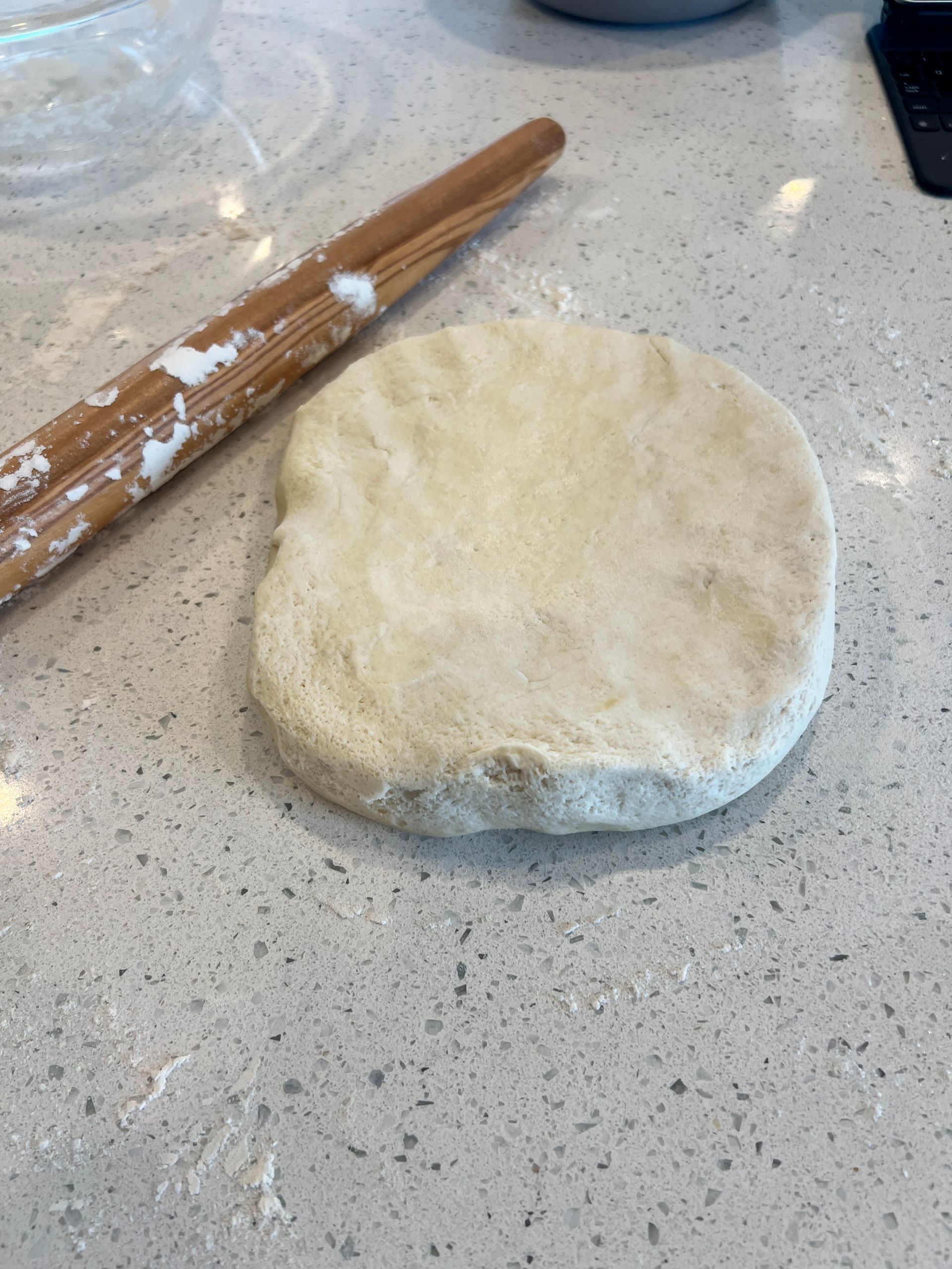 A piece of dough is sitting on a counter next to a rolling pin.