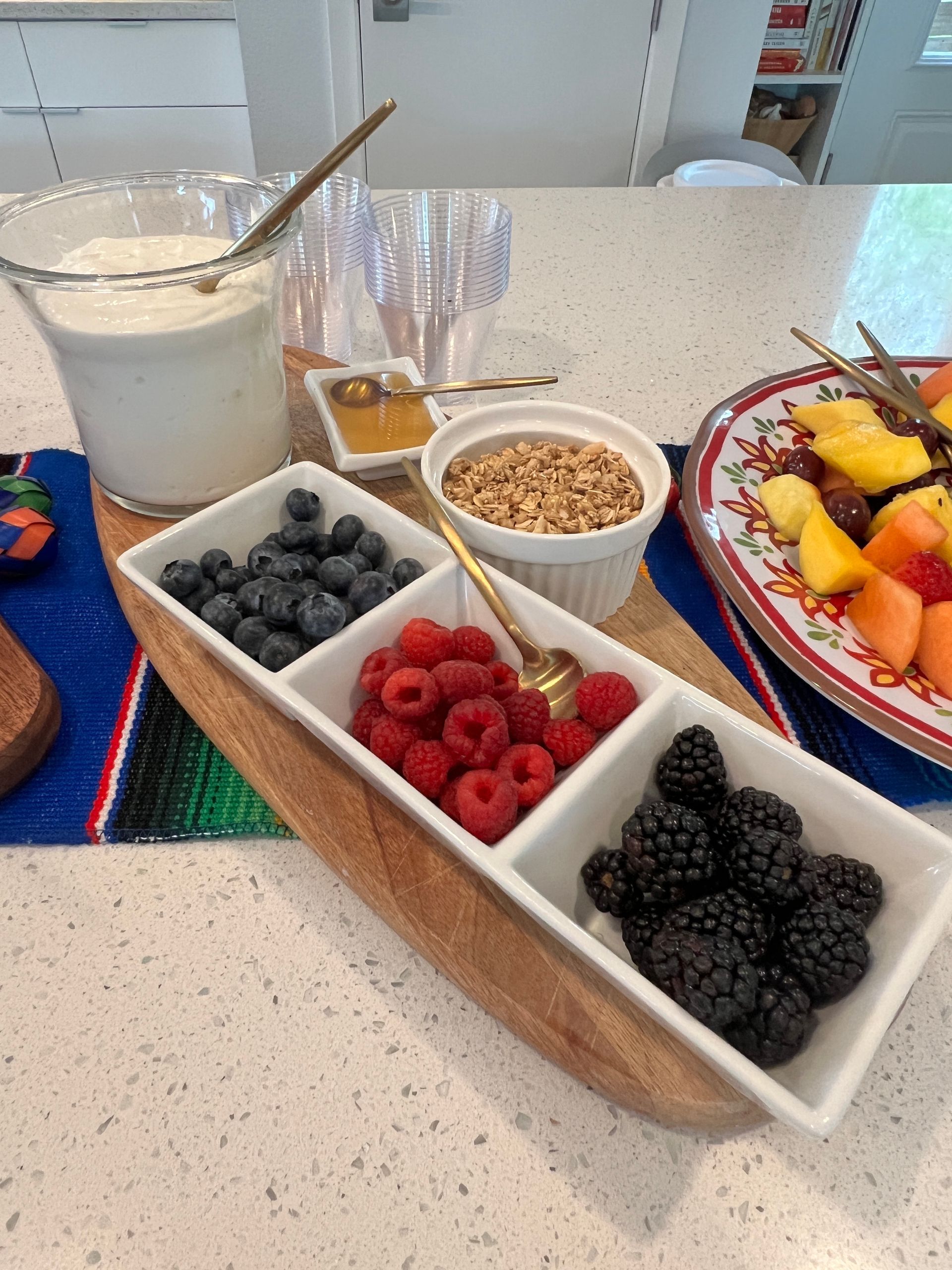 A wooden tray filled with fruit and yogurt on a counter.