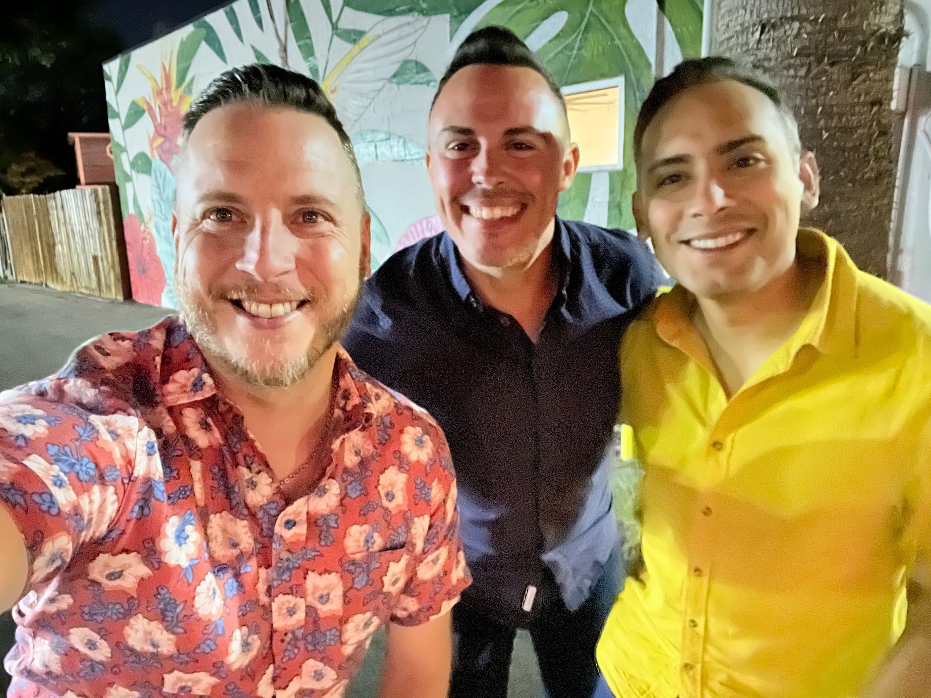 Three men are posing for a picture together and smiling.