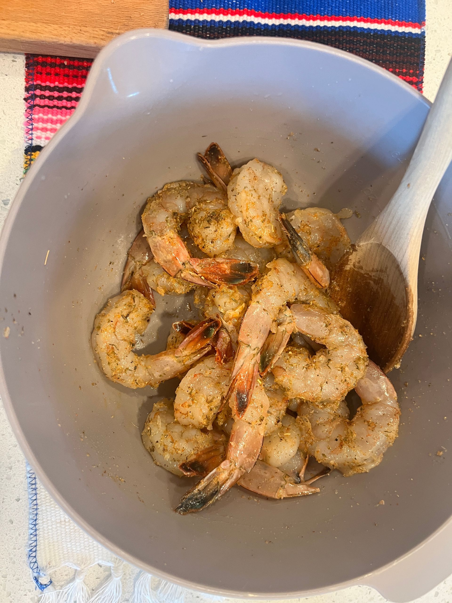 A bowl of shrimp with a spoon in it.