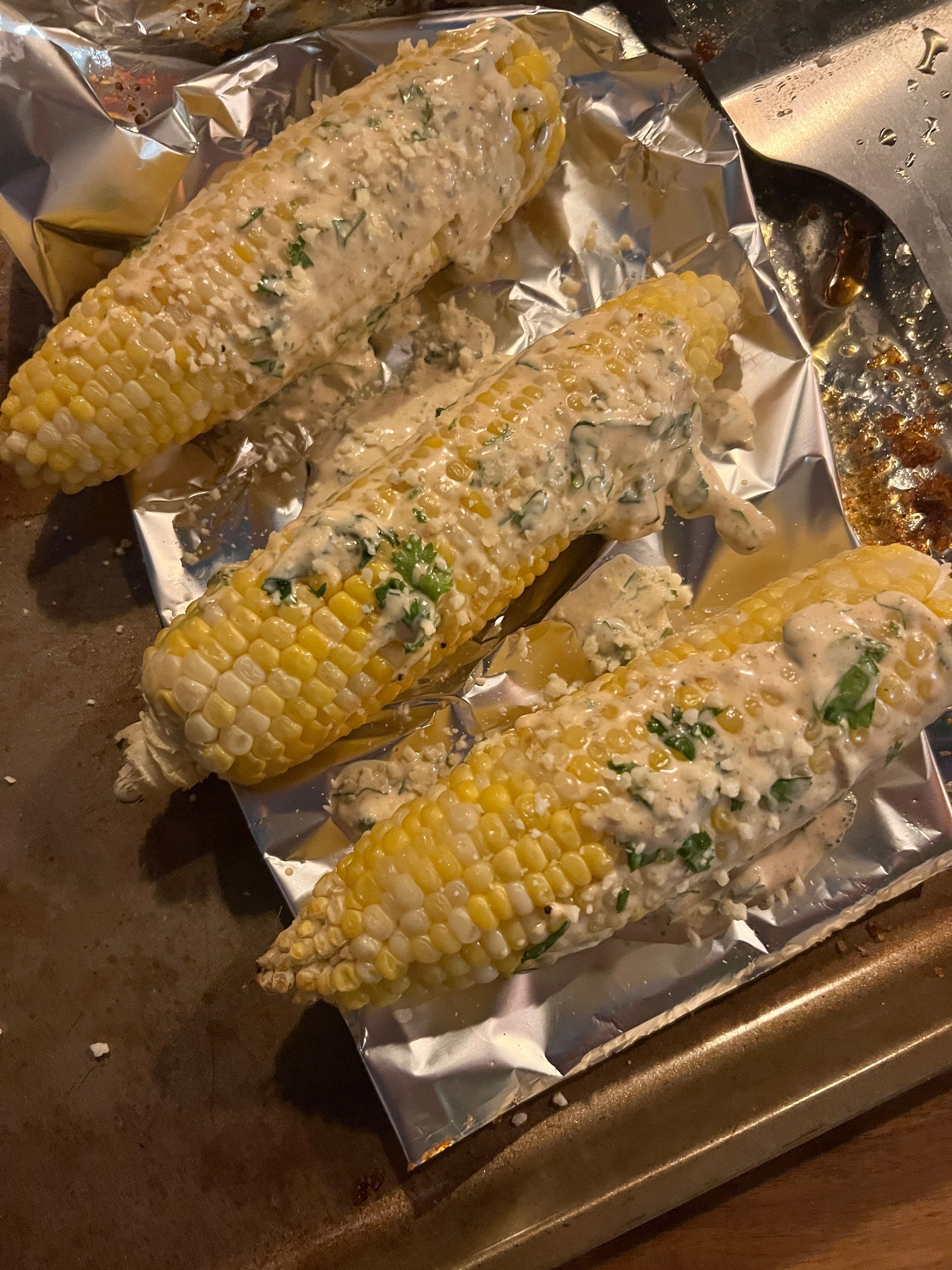 A close up of corn on the cob covered in sauce on a pan.