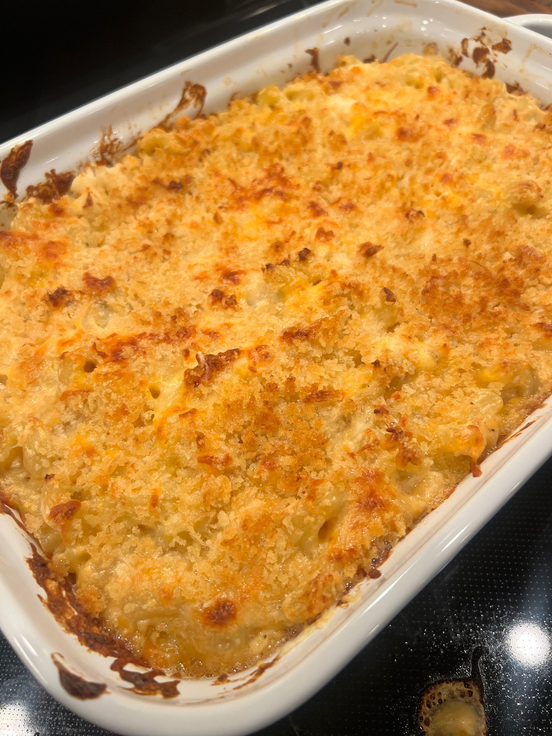A casserole dish filled with macaroni and cheese is sitting on a stove.