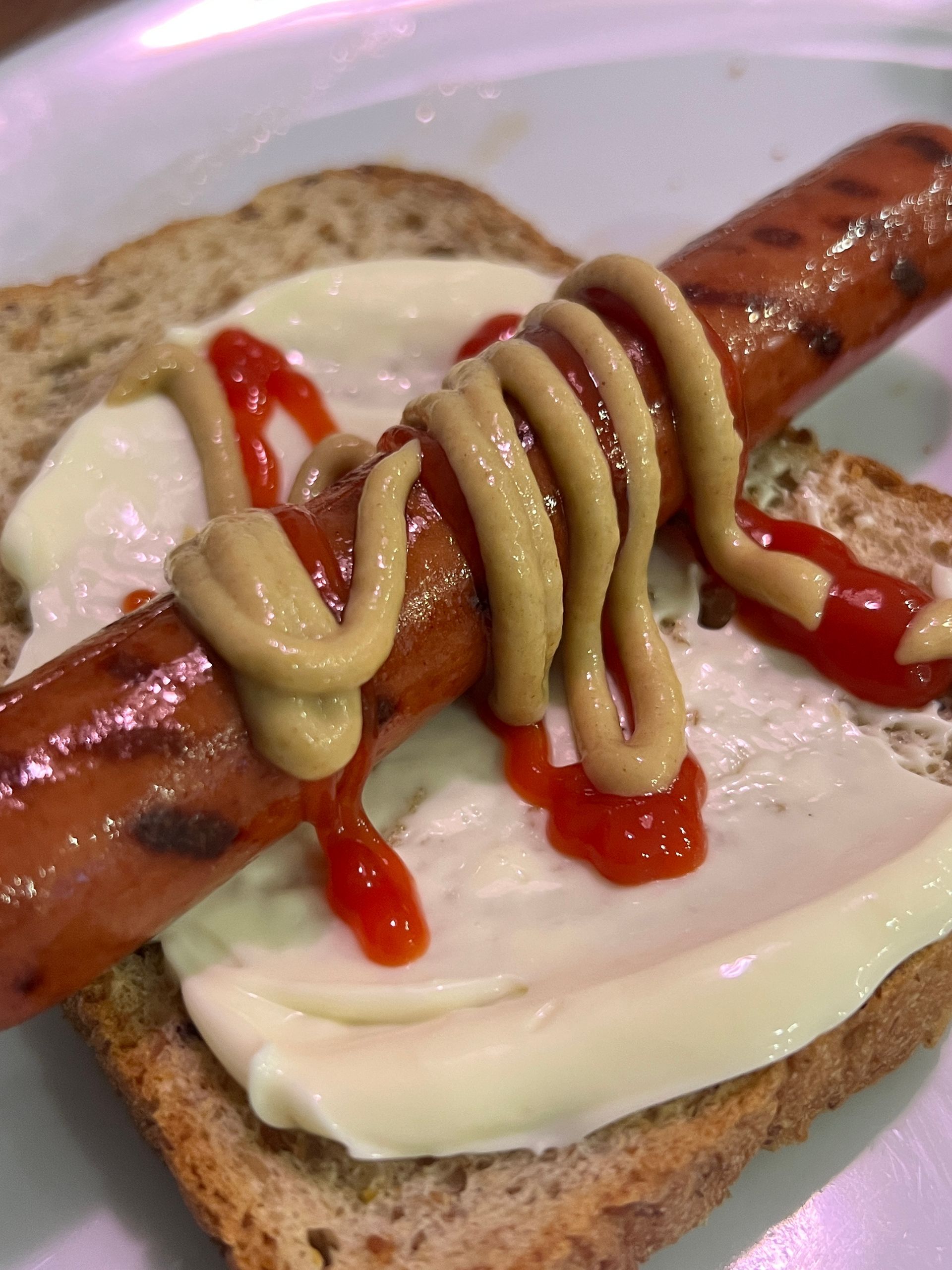 A hot dog with mustard and ketchup on a piece of bread