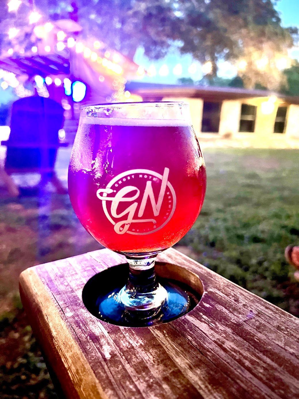 A glass of red beer is sitting on a wooden table.