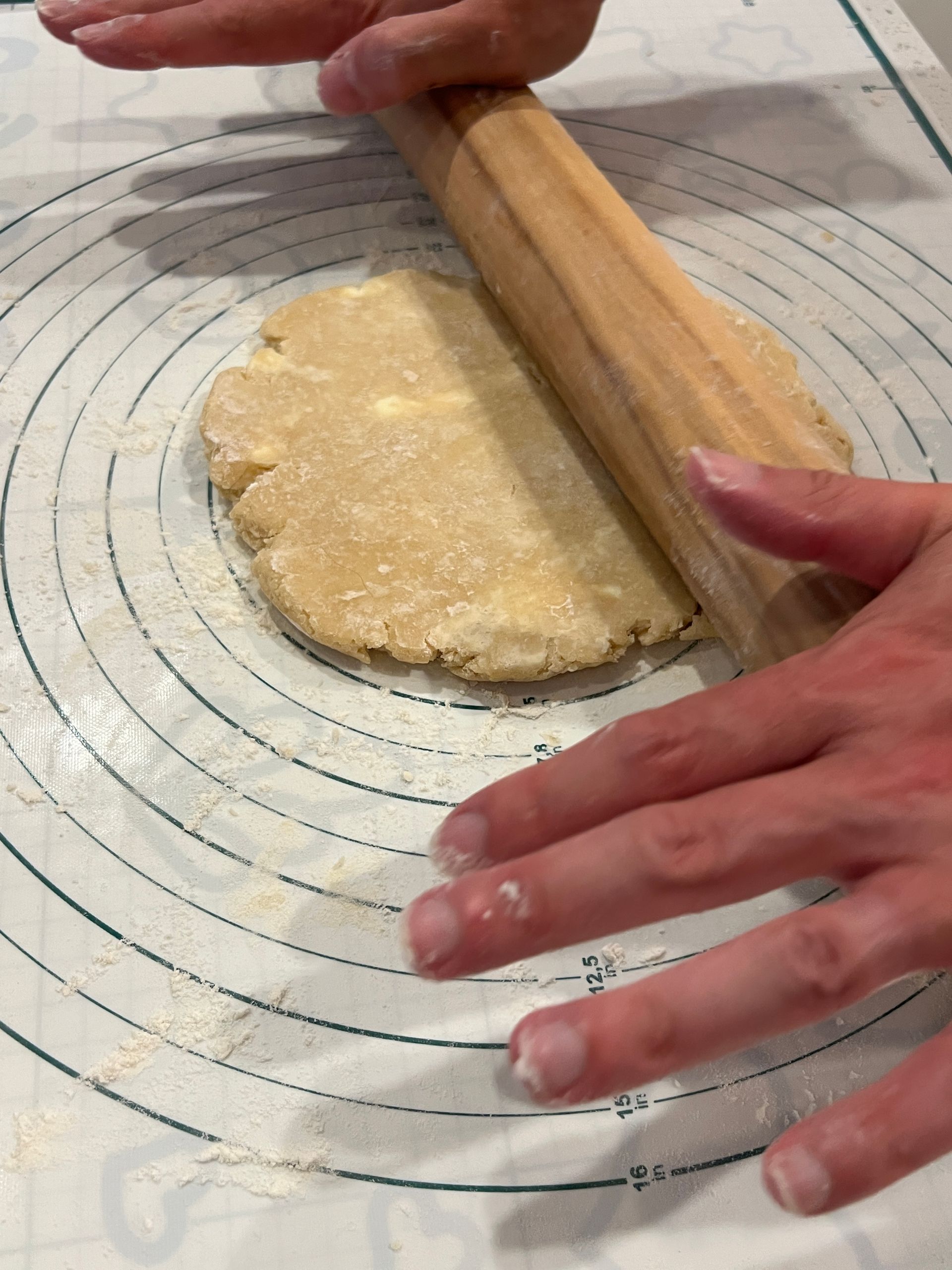 A person is rolling out a piece of dough with a rolling pin