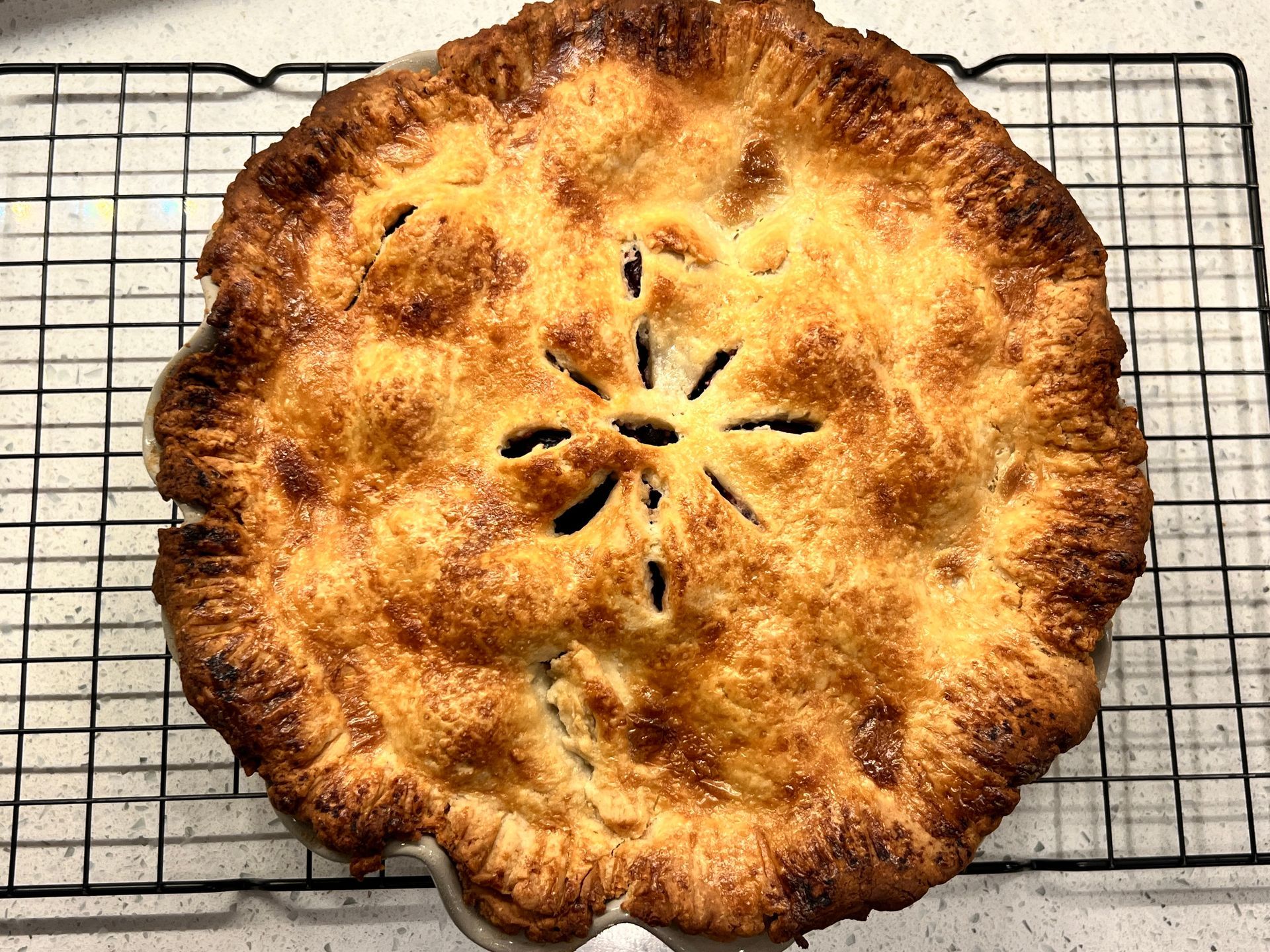An apple pie is sitting on a cooling rack.