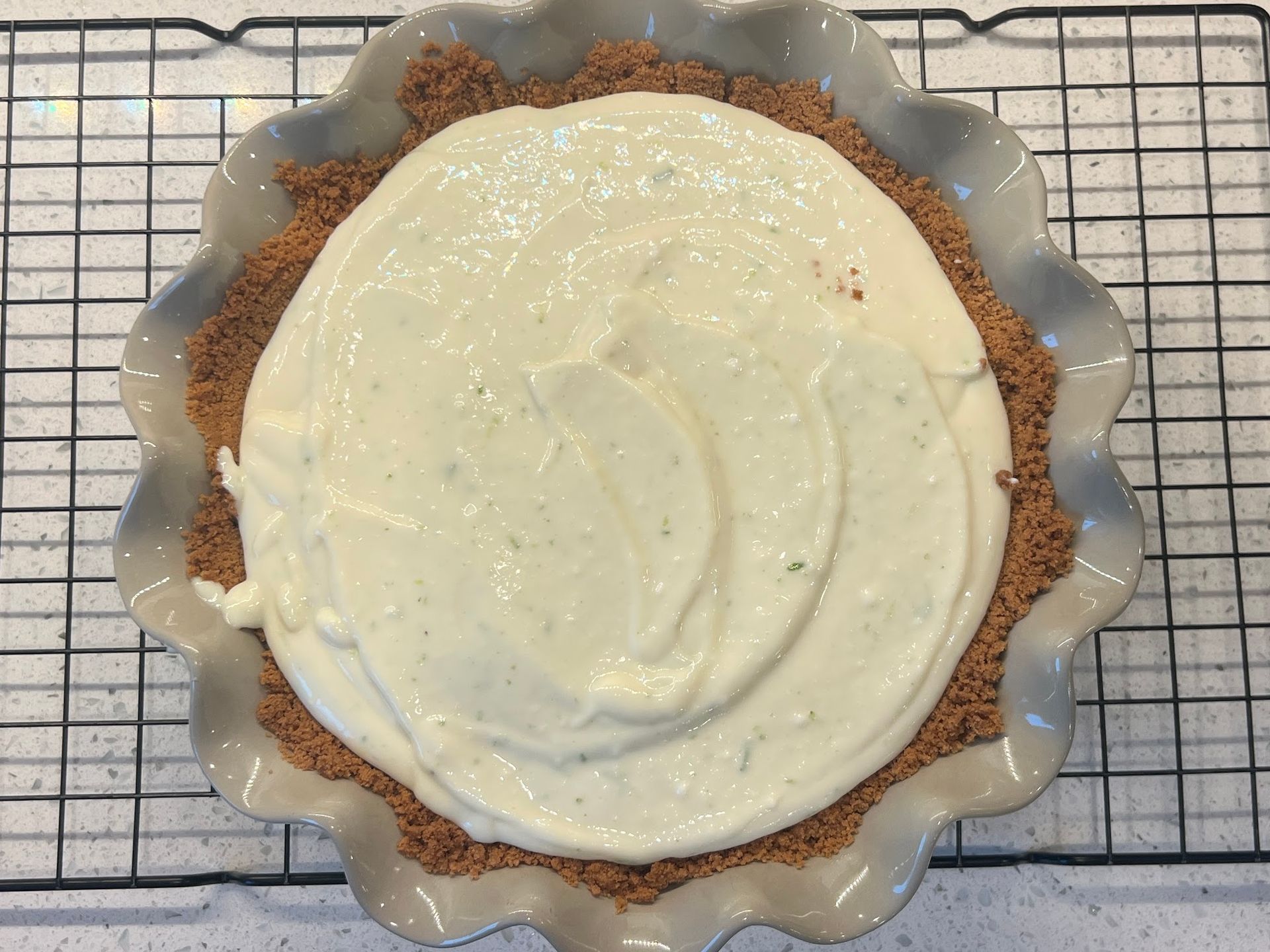 A pie crust is being filled with a creamy filling