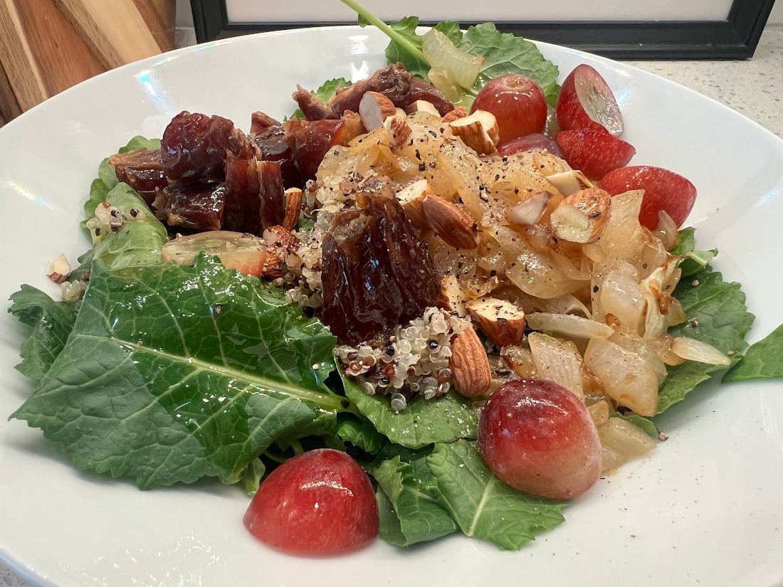 A white plate topped with a salad with grapes and nuts