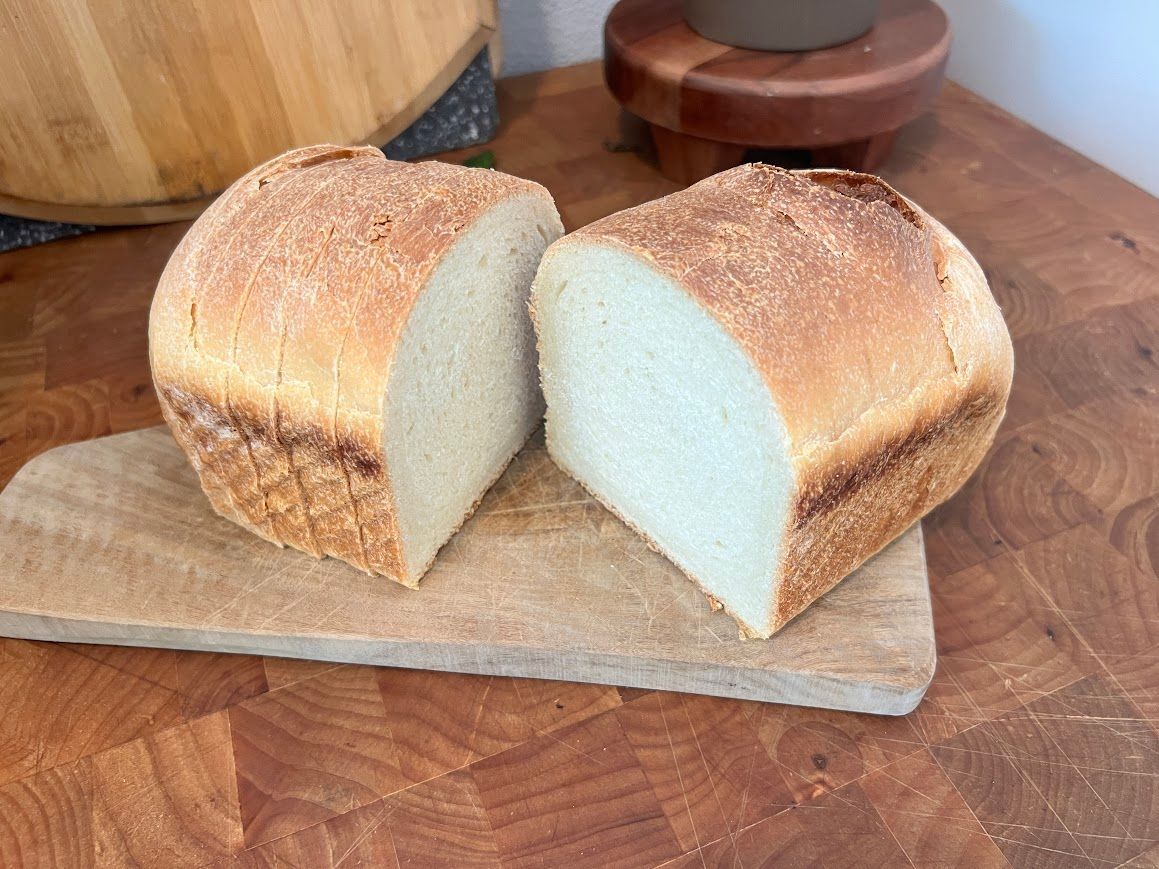 Two slices of bread are sitting on a wooden cutting board.