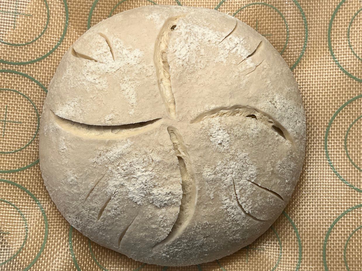 A loaf of bread is sitting on a mat on a table.