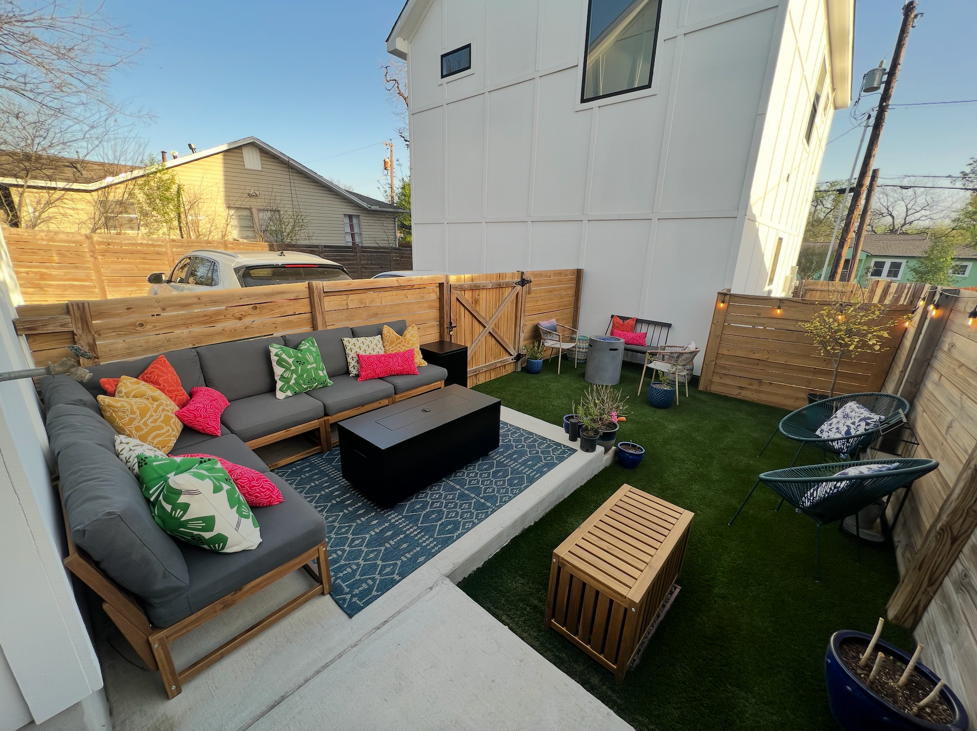 A backyard with a couch , table , chairs and a fence.