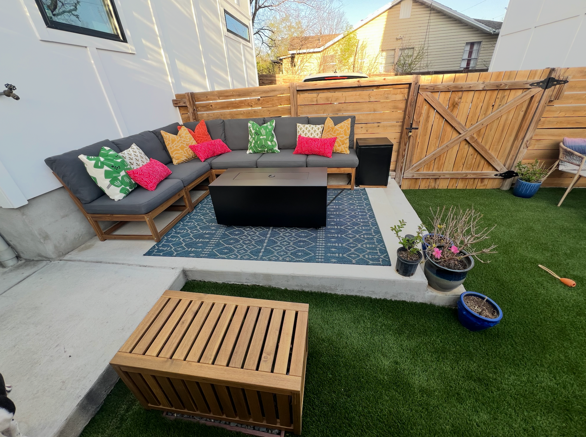 A backyard with a couch , table , and a dog.
