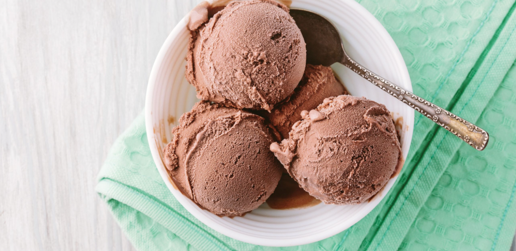 A bowl of chocolate ice cream with a spoon in it.