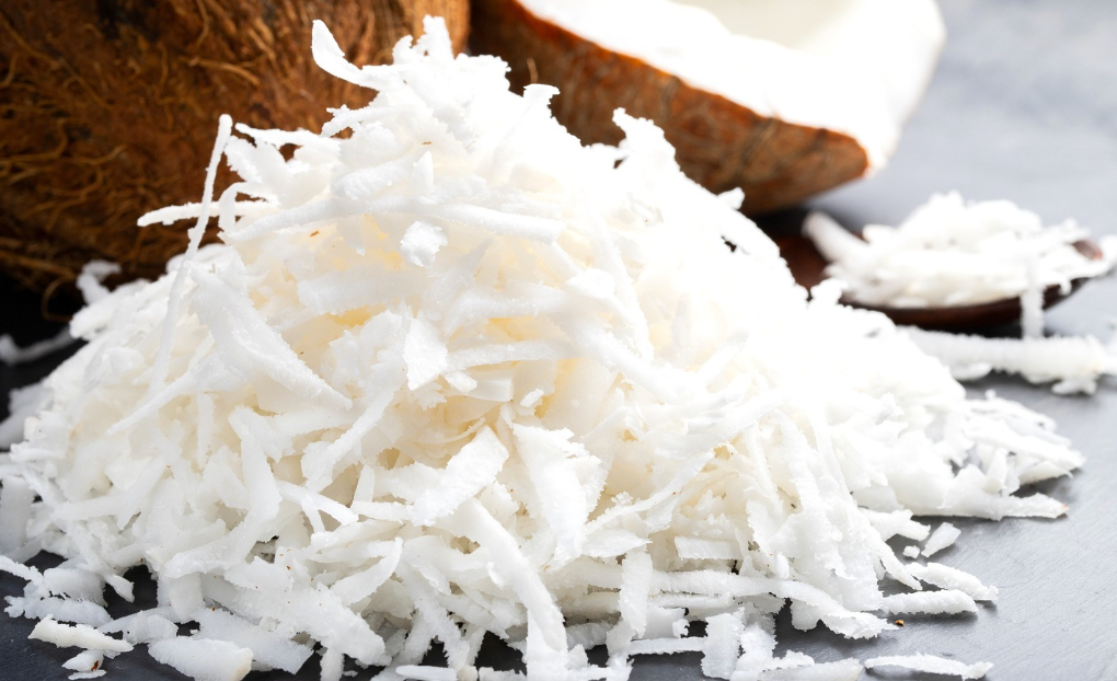 A pile of shredded coconut next to a coconut