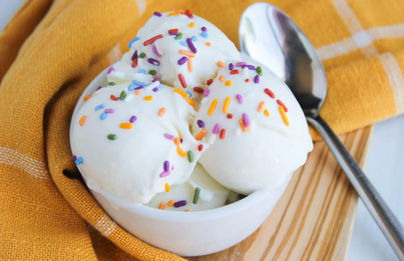 A bowl of ice cream with sprinkles and a spoon.