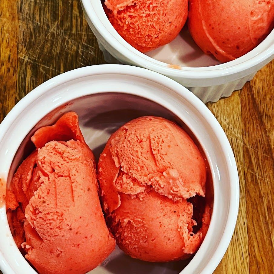 Two bowls of strawberry ice cream on a wooden table