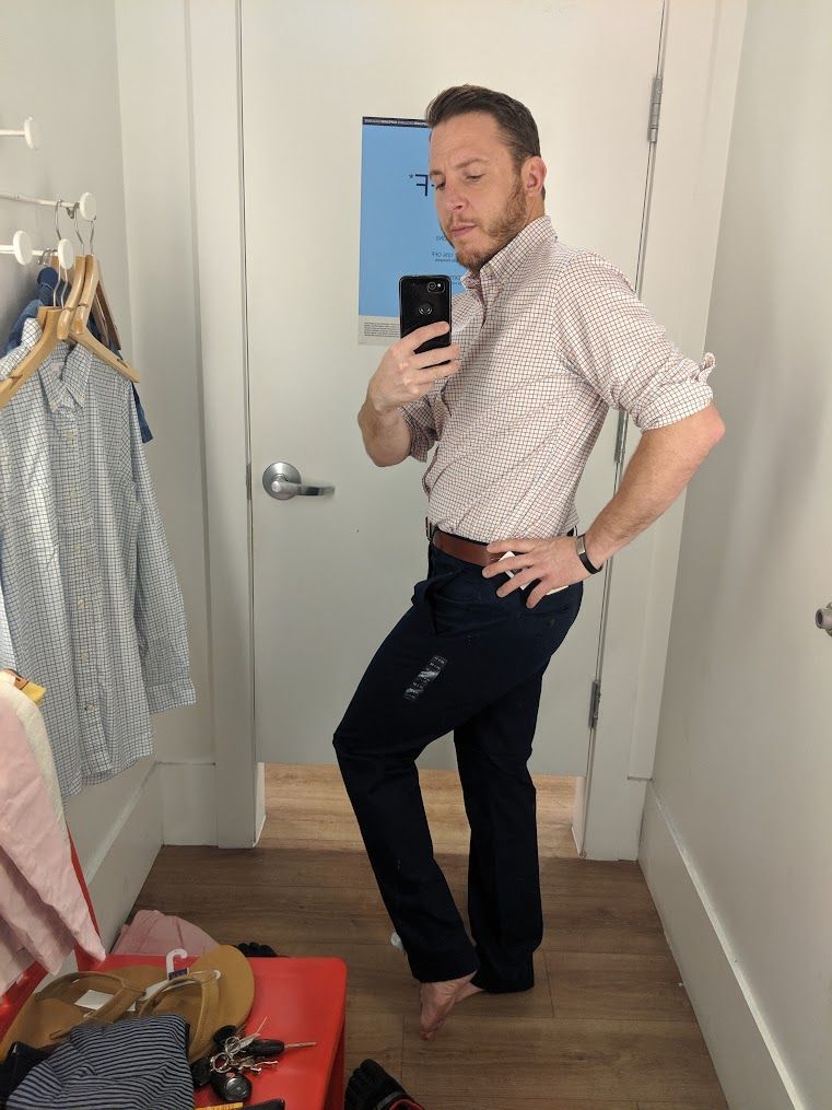 A man is taking a picture of himself in a dressing room.