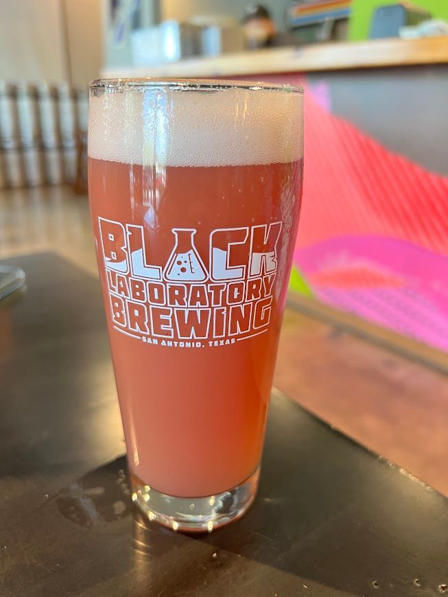 A glass of black experimental brewing beer is sitting on a table.