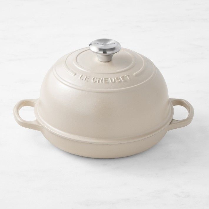 A white le creuset pot sits on a white surface