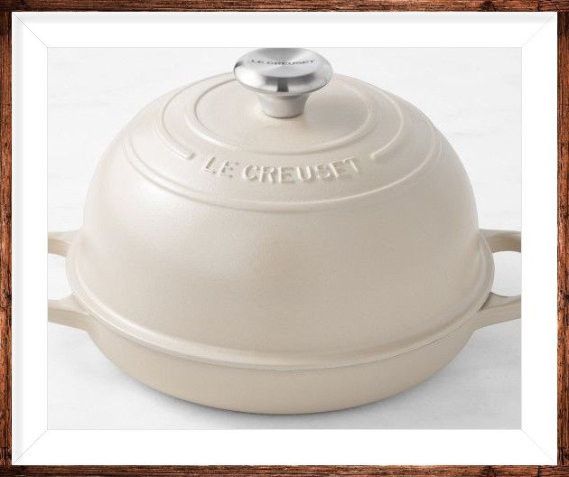 A white le creuset pot sits in a wooden frame