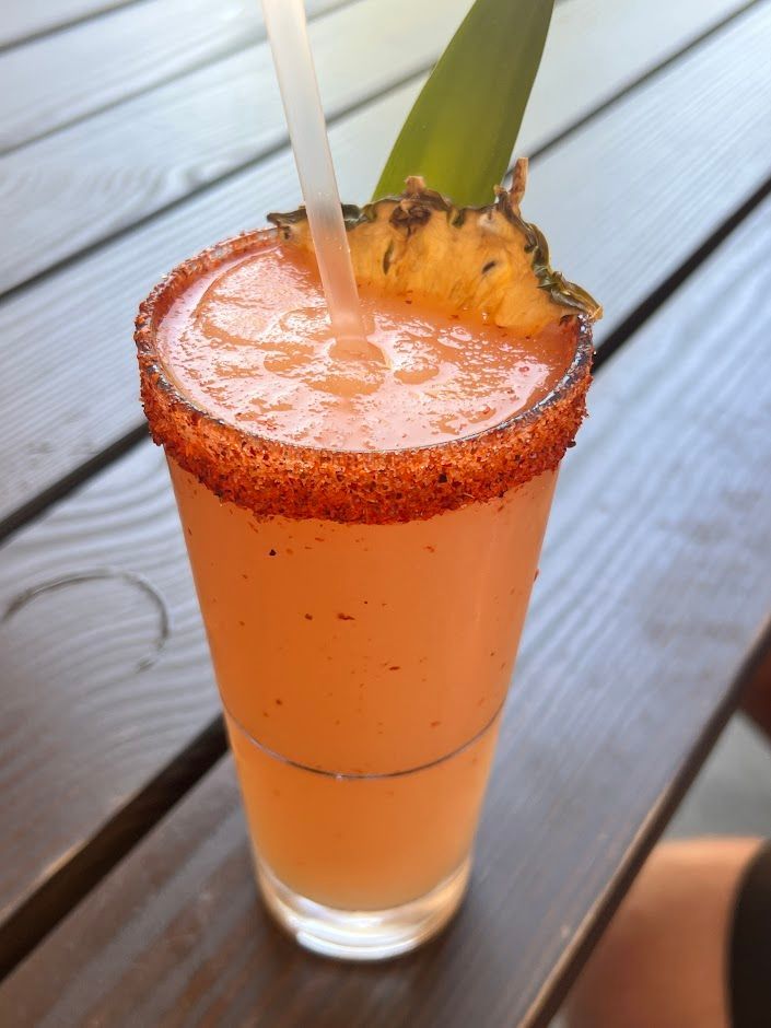 A drink in a tall glass with a pineapple slice on top