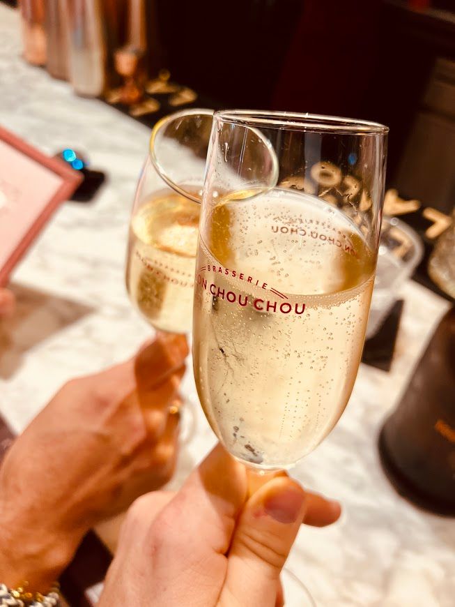 A person is holding two glasses of champagne in their hands.