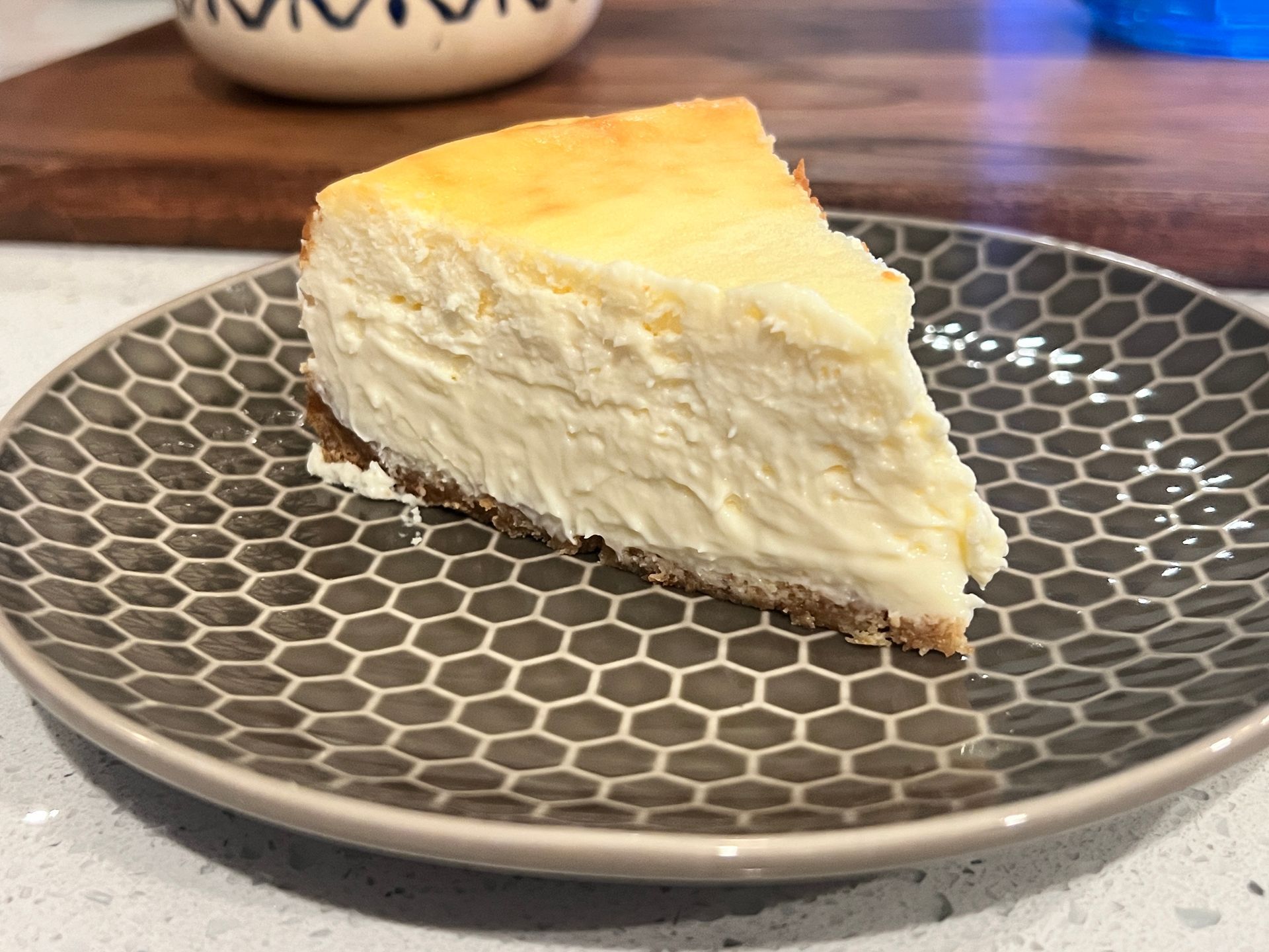 A slice of cheesecake is on a plate on a table.
