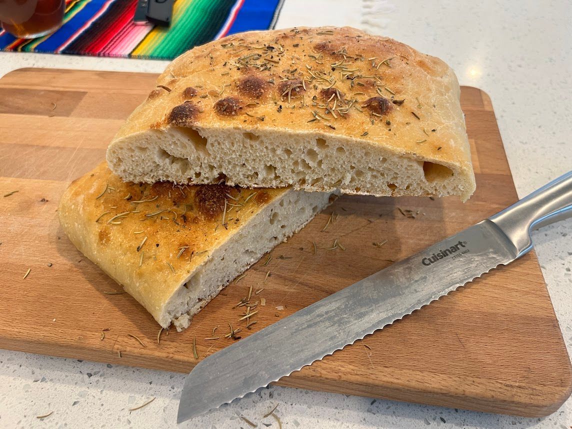 a loaf of focaccia is sitting on a cutting board