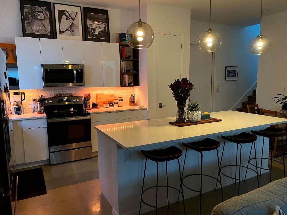 A kitchen with a large island and stools and a stove.