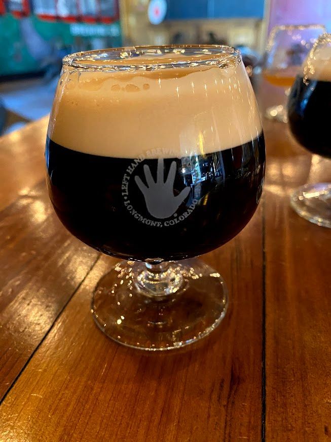 A glass of beer is sitting on a wooden table.