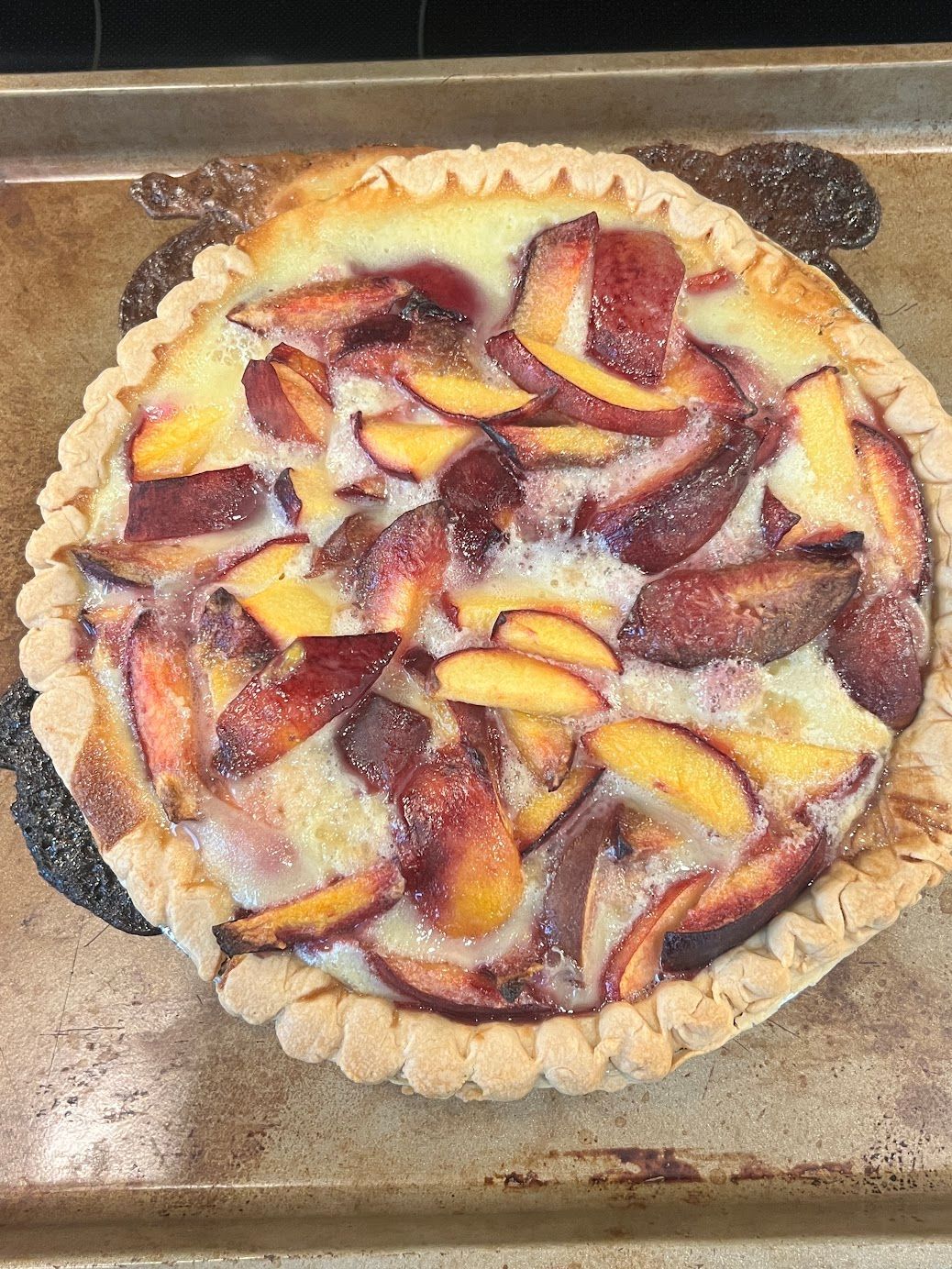 A pie with peaches on top of it is sitting on a pan.
